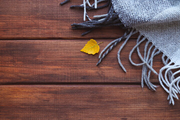 Autumn composition. Plaid and yellow autumn leaf on a wooden background with copy space. Top view