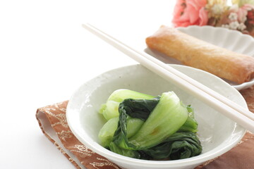 Chinese bowl green leaves vegetable and soy sauce with spring roll on background
