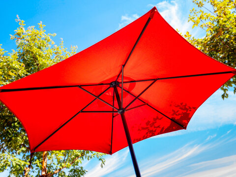 Underside of red patio umbrella and blue sky