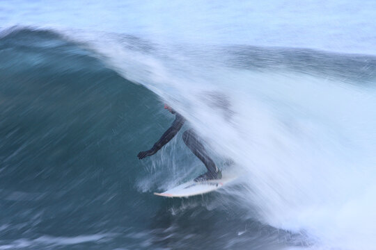 Surfer in a wetsuit on a surfboard in a cold water tube barrel in Vancouver Island, British Columbia, BC, Canada
