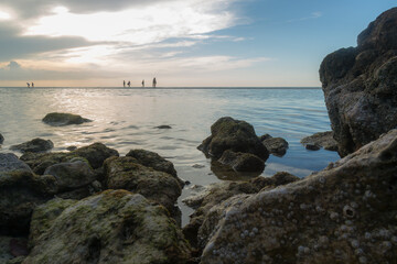 People walking and enjoying the sunset on a sandbar in the middle of the sea on Holbox Island in Mexico.
