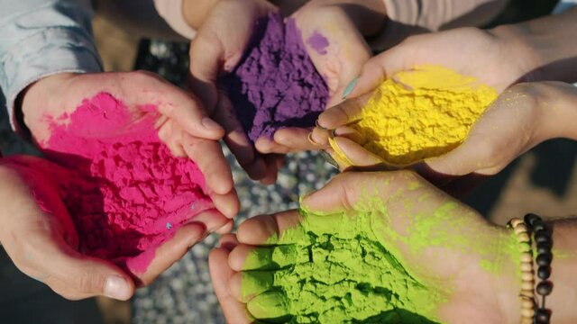 Close-up of human hands holding colorful powder paint gulal for Holi festival ceremony standing outside. People and ethnic celebration concept.
