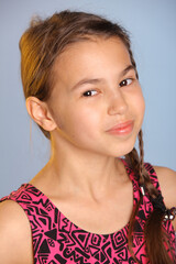 Close-up portrait of a bright cute dark-haired teenage girl 12 years old in a purple dress, her brown eyes laugh and look eye to eye.