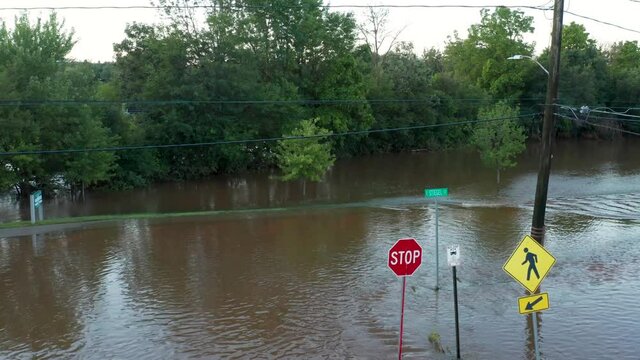 American town submerged in tropical storm hurricane flood waters. Streets, roads, signs under rain water. Rising aerial.
