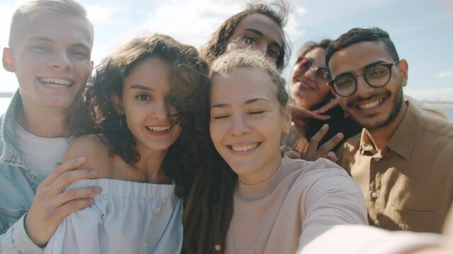 POV portrait of happy young people friends taking selfie having fun and looking at camera outdoors on warm summer day. Youth and photography concept.