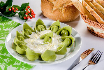 Macarrão de massa verde fresca de agnolotti com molho branco e queijo parmesão em mesa decorada.