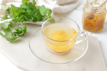 Cup of tasty tea with sea buckthorn on light background