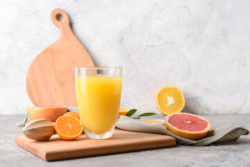 Glass with tasty citrus juice on grey background