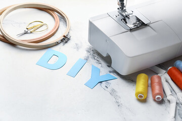 Composition with word DIY and sewing machine on light background