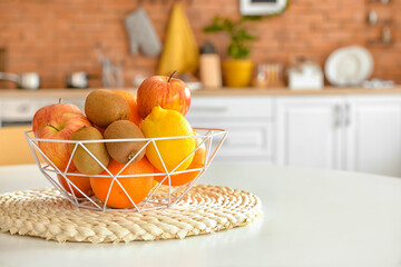 Basket with tropical fruits on table in kitchen