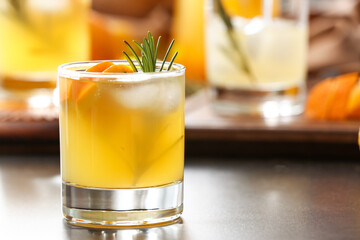 Glass of tasty orange cocktail with rosemary on table, closeup
