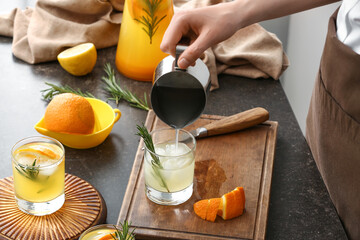 Woman pouring juice into glass on table in kitchen