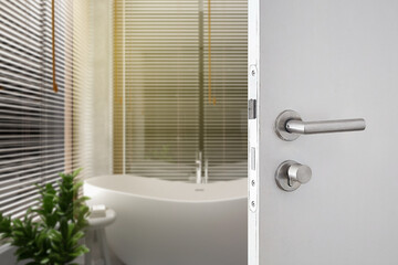 Door handle , door with stainless knob door half open in front of blurred interior bathroom background,  - obrazy, fototapety, plakaty