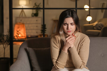 Obraz premium Religious young woman praying to God at home in evening