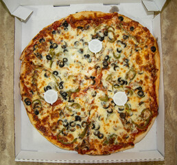 An oversized large pizza inside a carry out or to go box.