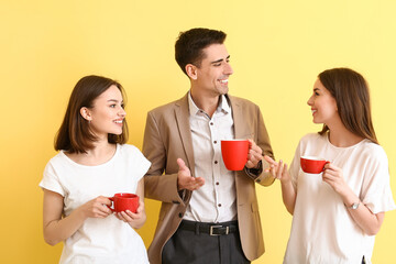 Business colleagues drinking coffee on color background