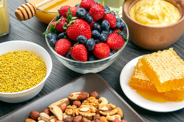 fresh assorted honey, nuts, strawberries and blueberries on a wooden background. healthy organic vitamin food.