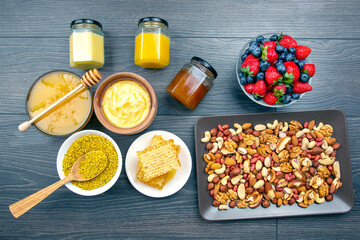 fresh assorted honey, nuts, strawberries and blueberries on a wooden background. healthy organic vitamin food.