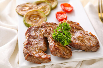 Plate with beef brisket and vegetables on fabric background