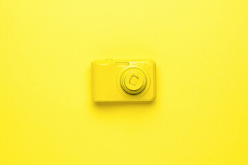 A bright yellow camera on a bright yellow background. Flat lay.