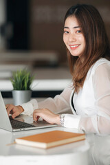 Portrait of asian woman working on laptop computer at office, vertical view.