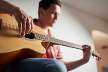 Young man playing guitar at home.
