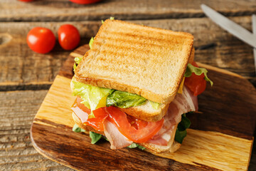 Board with tasty sandwich on wooden background, closeup