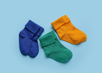 Different baby socks on color background