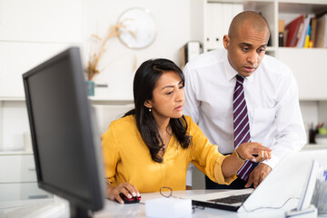 Obraz premium Focused male and female business colleagues looking at laptop screen, discussing new project in office