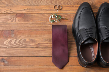 Wedding rings and groom accessories on wooden background
