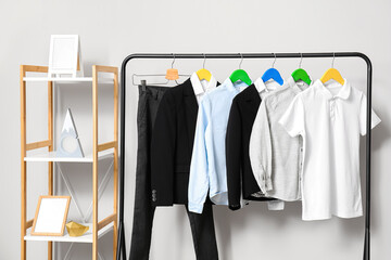 Rack with stylish school uniform near light wall