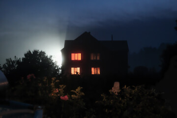 halloween concept. blurred defocused night time scene with hounted house and garden. foggy night,...