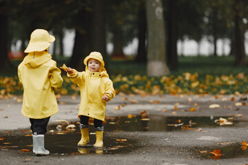 Funny kids in rain boots playing with a puddle