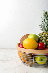 Basket with fresh fruits on light background