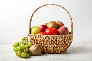 Basket with fresh fruits on light background