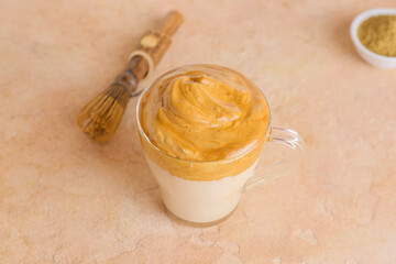Glass cup of tasty dalgona hojicha latte on color background