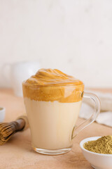 Glass cup of tasty dalgona hojicha latte on color background