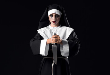 Woman dressed for Halloween as nun with knife on dark background