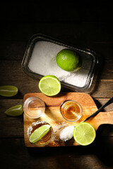 Shots of tasty tequila with lime on wooden background