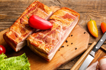 Tasty smoked bacon and fresh vegetables on wooden background