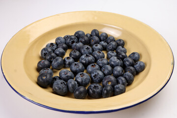 Fresh ripe deep purple Blueberry on old style metal enamel tin plate macro closeup