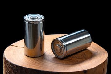 A pair of new modern high-capacity lithium-ion cells. A prototype of new batteries on a tree stump...