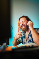 Funny man laughing during phone conversation in front of computer. Thumbs up