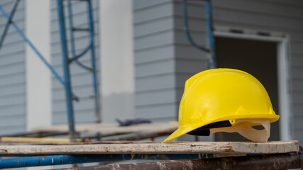 Safety helmet (hard hat) for engineer, safety officer, or architect, place on cement floor. Yellow safety hat (helmet) in construction site.