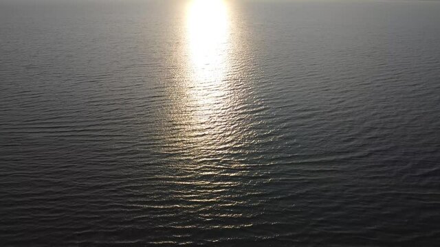 Waves at sea and the glow of the morning sun in the water. Aerial view. Glare of sunlight at sunrise.