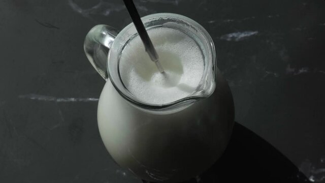Beat the milk in a mug using a frother. Hand mixer for milk. Making foamy with frother. Preparing milk for coffee. Step by step. Jug appliance starting up and turning around to froth white causing bub