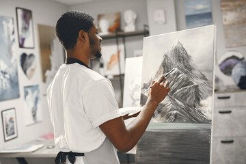 Young African-American artist painting picture in workshop