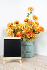 Wooden board easel mock up and Artificial flowers bouquet in metal vase on wooden table interior decoration