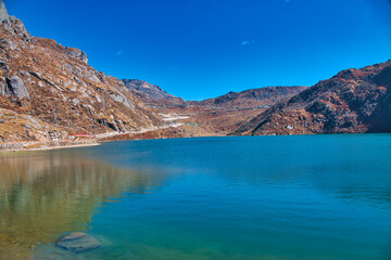 Fototapeta na wymiar An alpine lake surrounded by mountains. The water of the lake is blue. View of the mountains along the way. Travel to the Tsomgo Lake (Changu Lake), in the Indian state of Sikkim.
