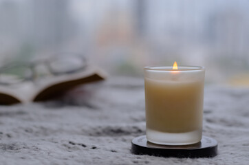 Flame burning at blurred aroma candle for relaxing when reading book at home in winter season. Zen and relax concept.